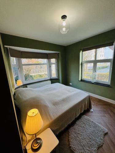 a bedroom with a bed with a lamp and two windows at Two bedroom apartment 150m from the beach in De Haan