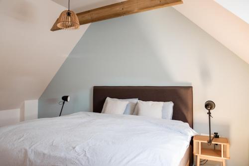 une chambre avec un lit blanc avec une tête de lit en bois dans l'établissement Neues Haus nahe des Leuchtturms, à Penmarcʼh