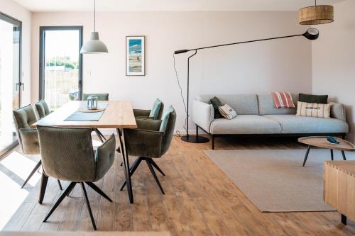 un salon avec une table, des chaises et un canapé dans l'établissement Neues Haus nahe des Leuchtturms, à Penmarcʼh