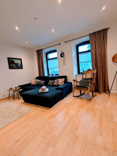 a living room with a black couch and some windows at Ferienwohnung am Rabenauer Grund in Freital
