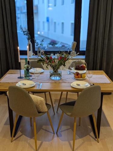 a wooden table with chairs and a vase of flowers at Ferienwohnung am Rabenauer Grund in Freital
