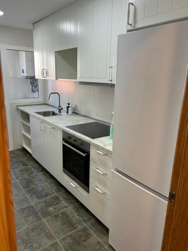 a kitchen with white cabinets and a white refrigerator at Apartamentos Suites Iscar in Iscar