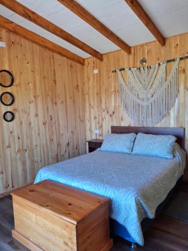 una camera con letto e parete in legno di Cabaña Refugio Magenta a Ñipas