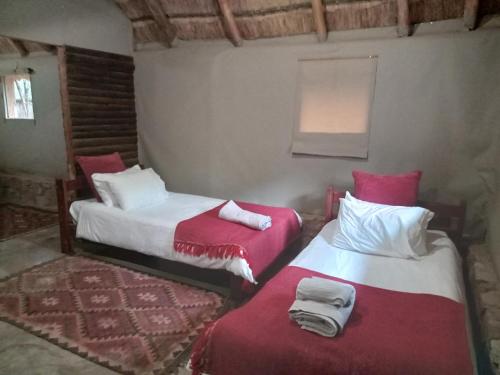 two beds in a room with red and white at Thandile River Cottages in Moheme