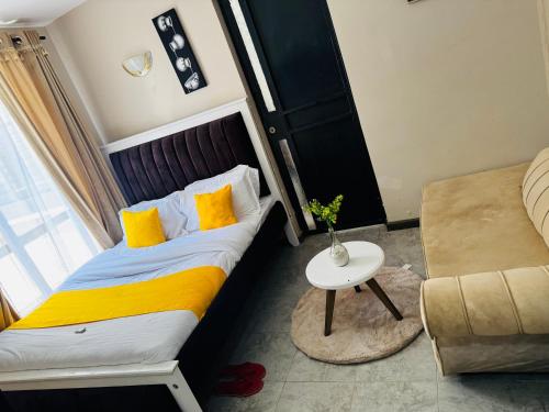 a bedroom with a bed and a table and a couch at A modern affordable stylish bedsitter centrally located in nairobi in Nairobi