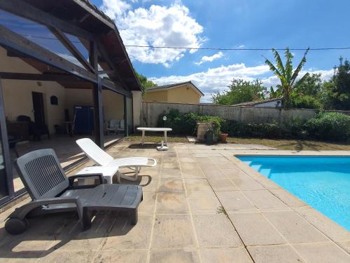 - une terrasse avec 2 chaises et une table à côté de la piscine dans l'établissement Villa avec piscine chauffée proche Toulouse centre, à LʼUnion