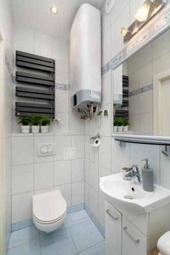 a white bathroom with a toilet and a sink at Caffe latte apartment in Krakow