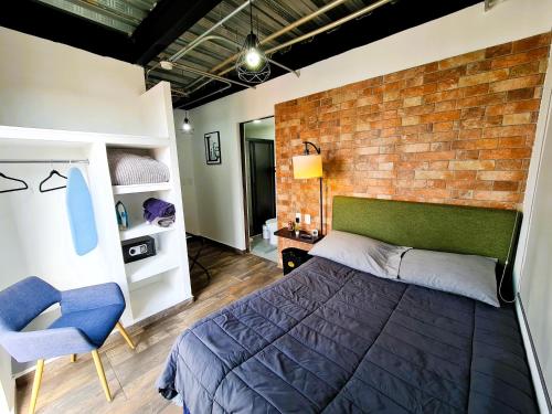 a bedroom with a brick wall and a bed and a chair at C46-R07 STUDIOS at ITESM CEM Families Tourists & Travelers Choice Foreign Students Companies Executives WELCOME!!! 10min Izcalli-15min Esmeralda-20min Sátelite-25min AIFA in Mexico City