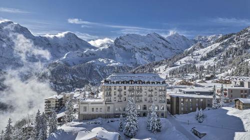 a building in the snow with mountains in the background at Hotel Mürren Palace in Mürren