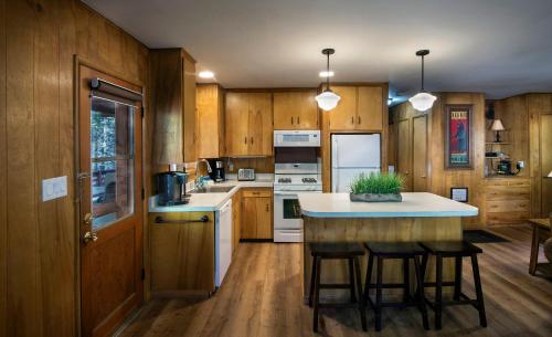 Una cocina con gabinetes de madera y una isla con taburetes de bar. en Pine Creek Cabin, en Wawona