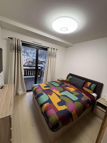 - une chambre avec un lit et une couverture colorée dans l'établissement Apartment Le Monde des Neiges, à Saint-Étienne-de-Tinée