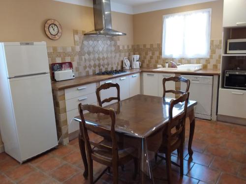 une cuisine avec une table et un réfrigérateur blanc dans l'établissement Casa Murtetu 3 étoiles, à Porto-Vecchio