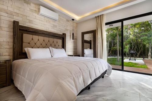 a bedroom with a large bed and a large window at ¡Increible! Villa Luz de Luna in Akumal