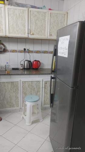 a kitchen with a stainless steel refrigerator and a stool at Muscat Galaxy Hostel in Muscat