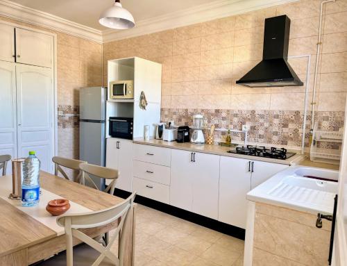 a kitchen with white cabinets and a table and a refrigerator at Appartement entier rénové à 5min de la Plage de Sousse in Sousse