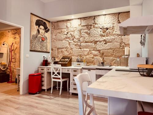 - une cuisine avec des placards blancs et un mur en pierre dans l'établissement L'Apothicaire, centre historique, climatisation, fibre, ESS, rez-de-chaussée, BedinShop, à Romans-sur-Isère