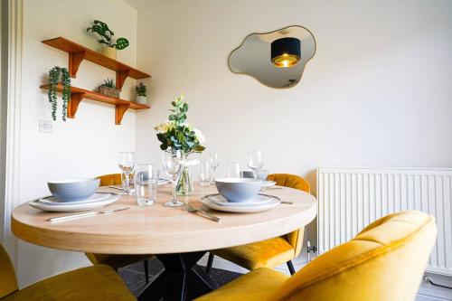 a wooden table with yellow chairs and a dining room at Harvest Way House Shortlets in Witney