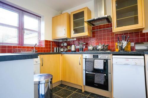a kitchen with wooden cabinets and a stove top oven at Harvest Way House Shortlets in Witney