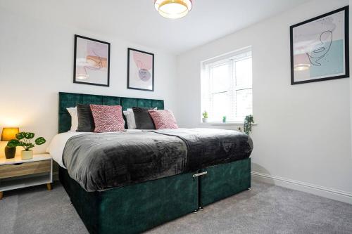 a bedroom with a large green bed with pink pillows at Harvest Way House Shortlets in Witney
