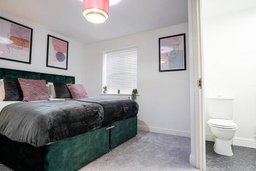 a bedroom with a green bed and a toilet at Harvest Way House Shortlets in Witney