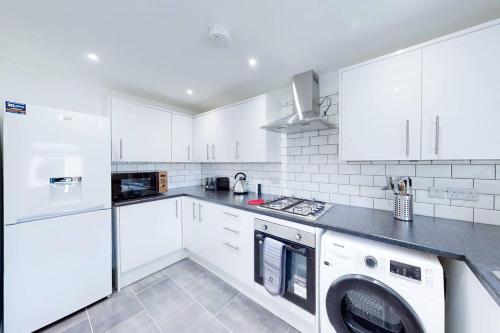 a kitchen with white cabinets and a washer and dryer at Ranworth-House - Perfect for professionals in Bedford