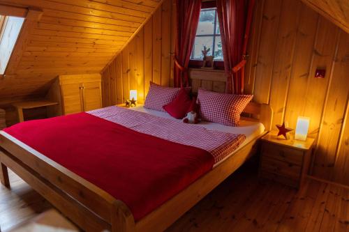 a bedroom with a large bed with a red blanket at HyggeZeit-im-Holzblockhaus-in-Wernigerode in Wernigerode