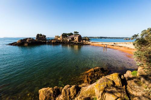 a beach with a house in the middle of the water at Le petit Tournebride in Paimpol
