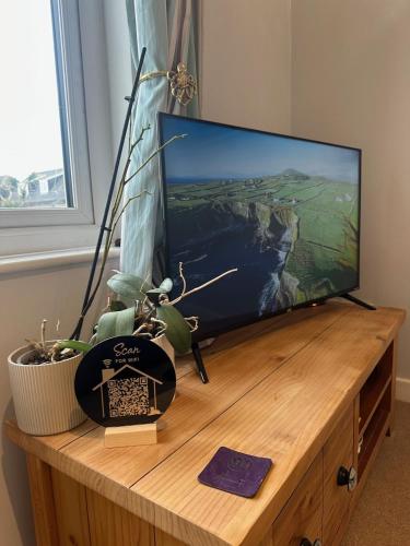 a flat screen tv sitting on top of a wooden entertainment center at Penolva Beach Side Apartment in Perranporth