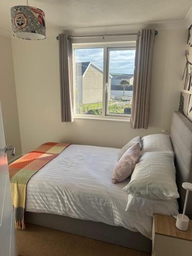 a bed with pillows and a window in a bedroom at Penolva Beach Side Apartment in Perranporth