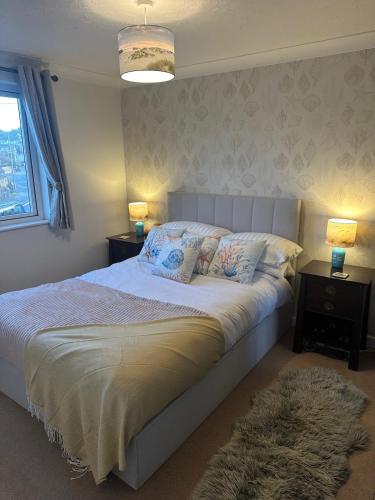 a bedroom with a bed with two night stands and two lamps at Penolva Beach Side Apartment in Perranporth