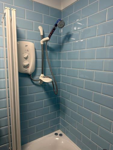 a blue tiled bathroom with a shower and a toilet at Penolva Beach Side Apartment in Perranporth