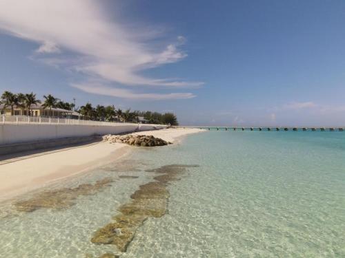 a beach with clear water and a white fence at Nautical Bimini Bay Villa with Starlink in Bailey Town