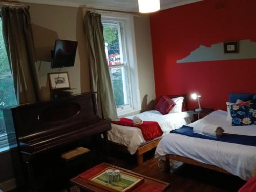 a red room with a piano and a bed and a table at TableMountain CityHub in Cape Town