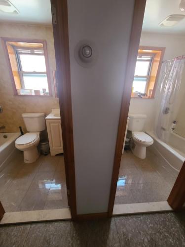 a bathroom with two toilets and a sink and a tub at Nice rooms Woodside in Queens