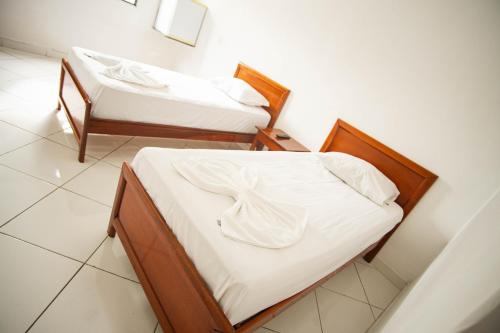 two beds with white sheets in a room at Hotel Virginia in Linhares