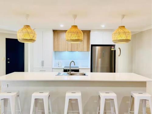 a kitchen with a white counter and white stools at Busselton Beach Villa - Family & Pet Friendly in Geographe