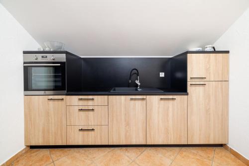 a kitchen with wooden cabinets and a sink at Apartments Sofija in Fužine