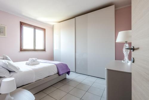 a white bedroom with a bed and a window at Hostly-Family Home Fosso Vecchio-Relax in Tuscany in Cascina