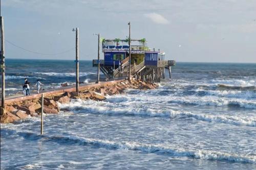 a pier in the ocean with waves at Ocean & Pool Views on seawall - Shoreline Stays 10 in Galveston