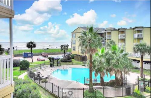 a view from the balcony of a resort with a pool and palm trees at Ocean & Pool Views on seawall - Shoreline Stays 10 in Galveston