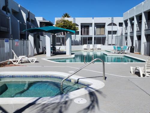 ツーソンにあるLas palmas Hotel Tucsonの傘付きのスイミングプール