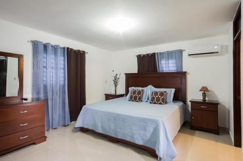 a bedroom with a large bed with blue curtains at Cozy, comfortable three-bedroom condo in Santiago,DR in Santiago de los Caballeros