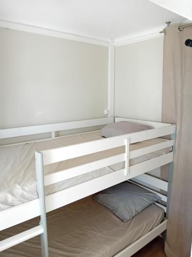 Ce lit superposé blanc se trouve dans un dortoir. dans l'établissement La Baie de Tamaris Appartement 4 couchages proche plage, à La Seyne-sur-Mer