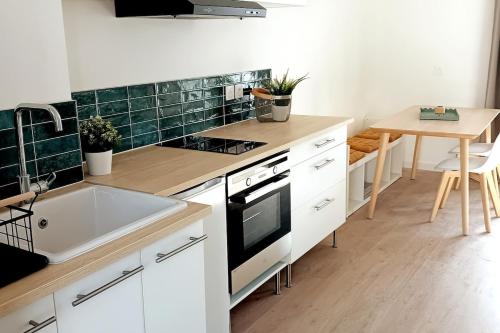 - une cuisine avec des placards blancs, un évier et une table dans l'établissement La Baie de Tamaris Appartement 4 couchages proche plage, à La Seyne-sur-Mer
