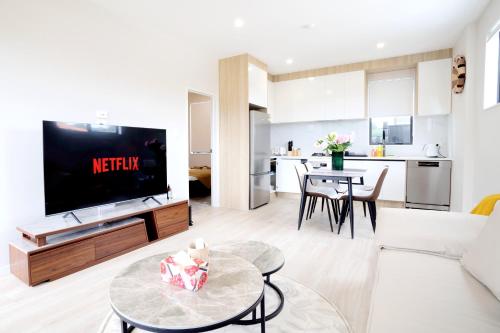 a living room with a couch and a tv and a table at 4 bedrooms Retreat with Netflix with Prime Location in Auckland