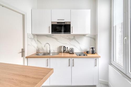 une cuisine blanche avec un évier et un micro-ondes dans l'établissement Le Majorelle - Hypercentre - Quartier Apaisant, à Angers