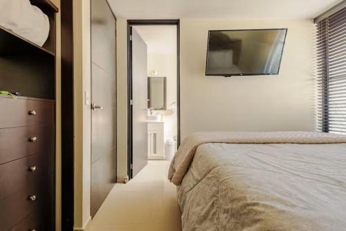 a bedroom with a bed and a tv on the wall at Shinyado CDMX in Mexico City