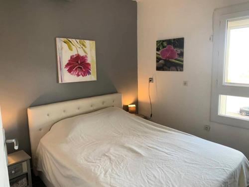 białe łóżko w sypialni z dwoma zdjęciami na ścianie w obiekcie Résidence Port Nature Colline 5 - Studio pour 2 personnes numéro 529 - Naturiste w Cap d'Agde