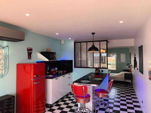 Il comprend une cuisine équipée d'un réfrigérateur rouge et de chaises rouges. dans l'établissement Résidence Port Nature Colline 4 - 2 Pièces 2 Personnes n477 - Naturiste, au Cap d'Agde