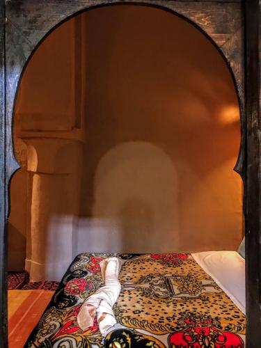 a person laying on a bed in a room at Riad La Perle Tamnougalte in Agdz